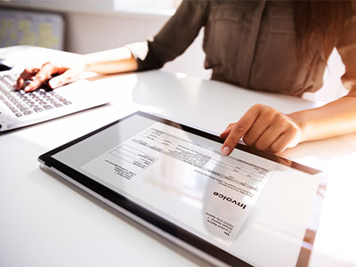 woman pointing to an invoice on her tablet at a desk - tungsten network total ap