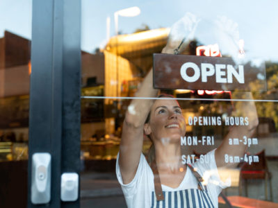 Happy business owner hanging an open sign at a café