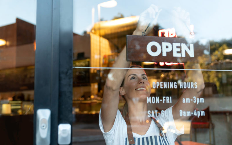 Happy business owner hanging an open sign at a café