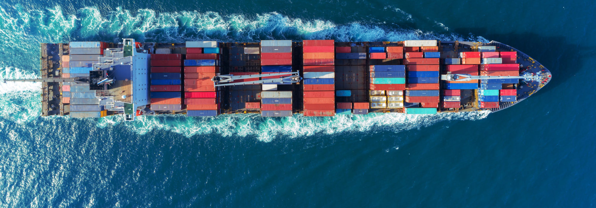 Aerial view Top speed with beautiful wave of container ship full load container with crane loading container for logistics import export or transportation concept background