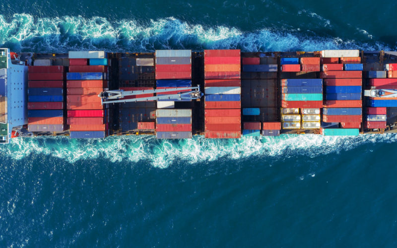 Aerial view Top speed with beautiful wave of container ship full load container with crane loading container for logistics import export or transportation concept background