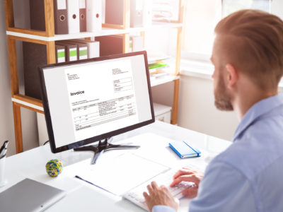 Businessperson Calculating E-Invoice Online On Computer At Office