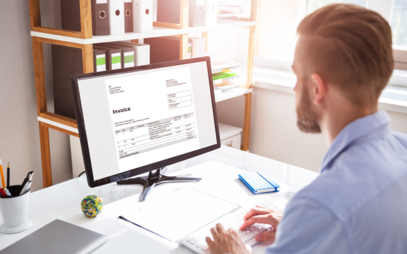 Businessperson Calculating E-Invoice Online On Computer At Office