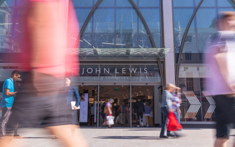 Busy Shoppers in the centre of Cheltenham in The Cotswolds, walking past the new John Lewis & Partners store in the High Street