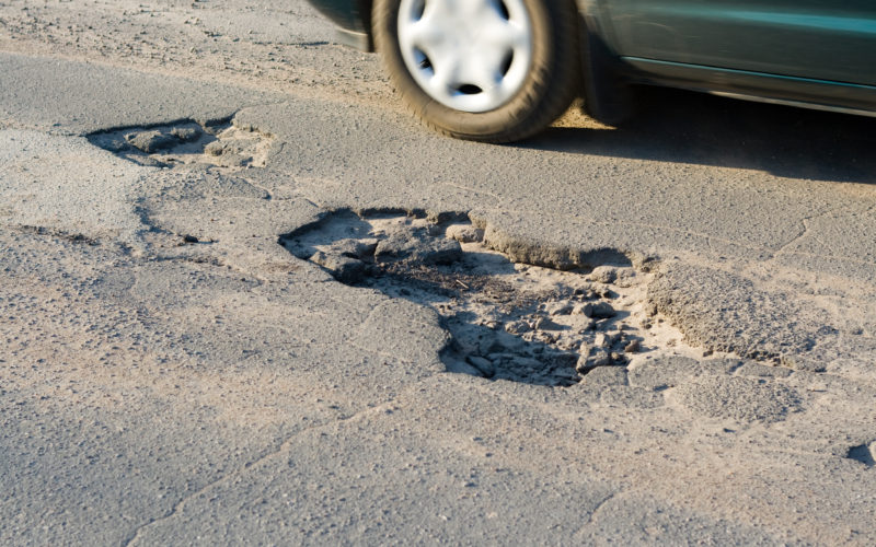 Asphalt`s holes on roadbed. Car in a motion.