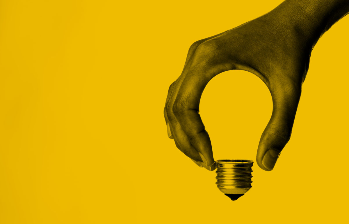 Light bulb in human hand on a yellow background