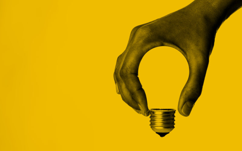 Light bulb in human hand on a yellow background