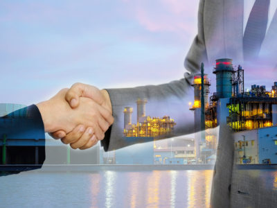 businessmen handshake on the factory background