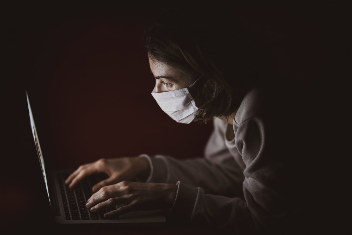 woman wearing a mask in front of a computer
