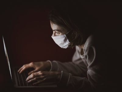 woman wearing a mask in front of a computer
