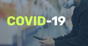 Man in Mask on Cell Phone | The Impact of COVID on Global Compliance - Featured Image