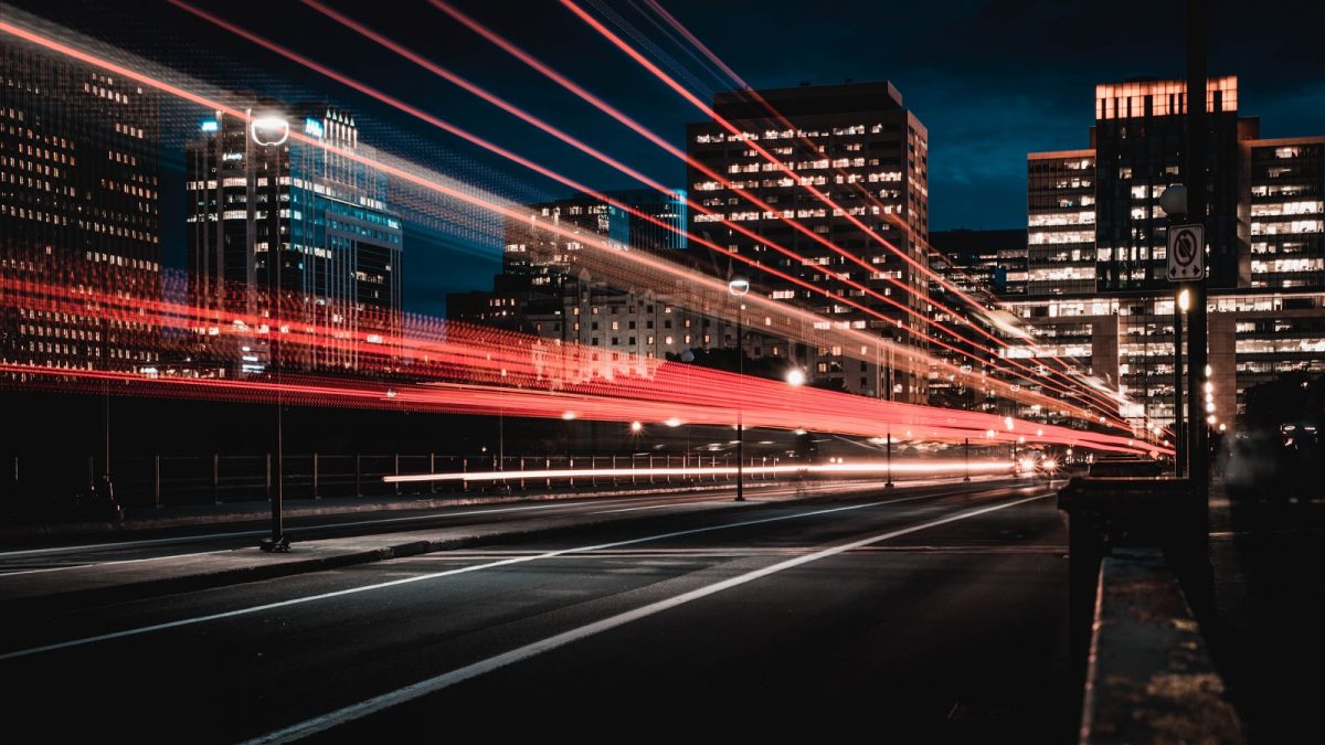 Long process photo technique showing blurred lights from cars on highway, with city behind at night | The Top Three Benefits of Automated Accounts Receivable