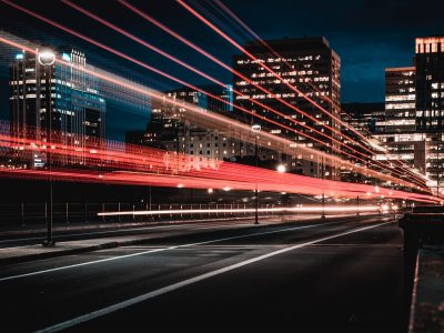 Long process photo technique showing blurred lights from cars on highway, with city behind at night | The Top Three Benefits of Automated Accounts Receivable