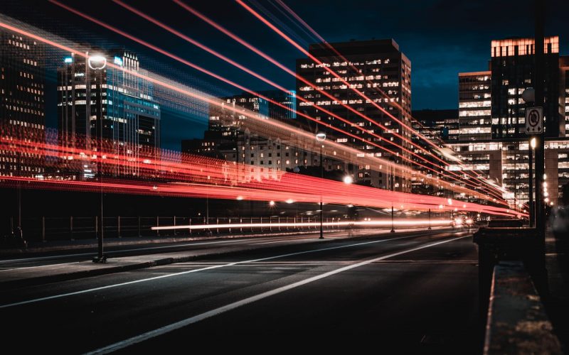 Long process photo technique showing blurred lights from cars on highway, with city behind at night | The Top Three Benefits of Automated Accounts Receivable