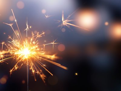 Glittering burning sparkler against blurred bokeh light background