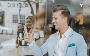 Man in a café smiling at his mobile phone