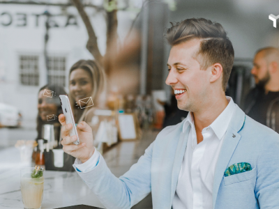 Man in a café smiling at his mobile phone