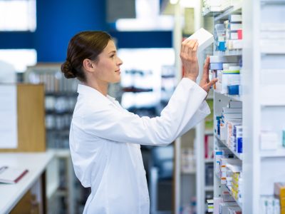 Pharmacist checking medicine in shelf