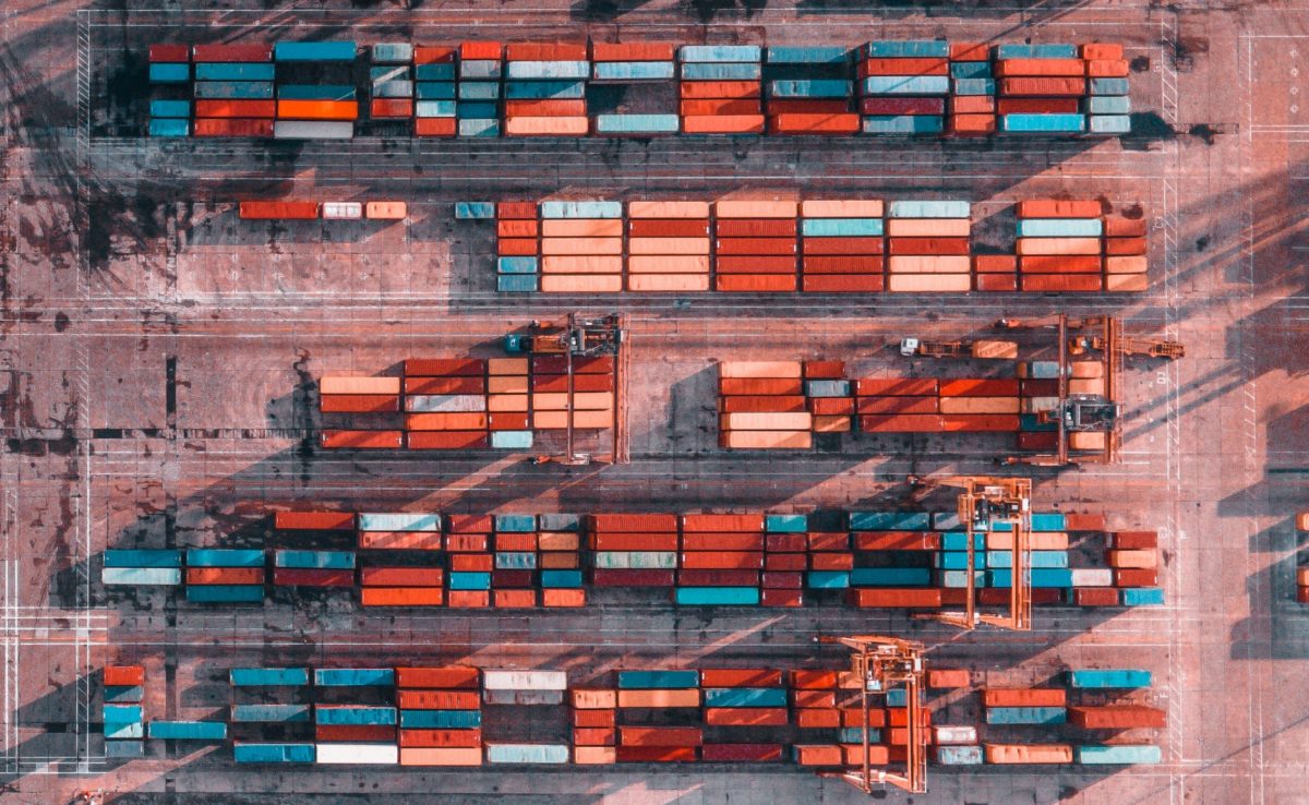 aerial view of an abandoned shipping yard, with different colored shipping containers, symbolizing the effect of COVID on supply chains, and the need for P2P automation