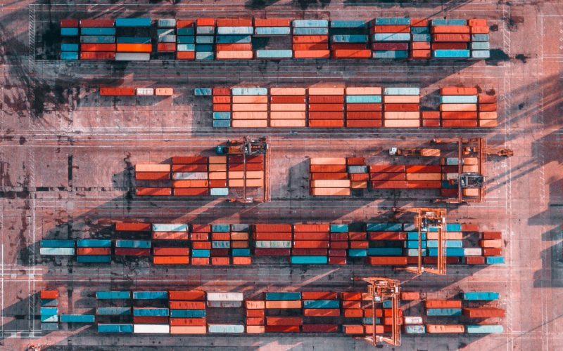 aerial view of an abandoned shipping yard, with different colored shipping containers, symbolizing the effect of COVID on supply chains, and the need for P2P automation